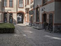 the two bicycles are parked next to each other outside the house, with cobblestone walkway going by the building