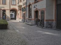 the two bicycles are parked next to each other outside the house, with cobblestone walkway going by the building
