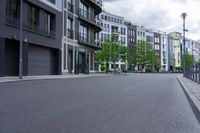 the city road is lined with apartment buildings along side it with people walking and riding