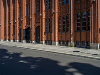 a person riding a bike down a street past a tall building with red brick walls