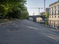 an empty street next to the buildings and some trees and a street light and some cranes