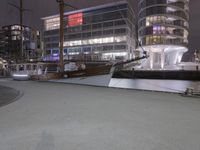 a man on a skateboard on a city street at night with buildings and a boat