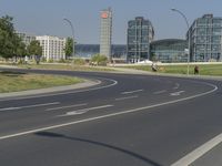 the street with two cars is empty in front of some city buildings by water in a sunny day