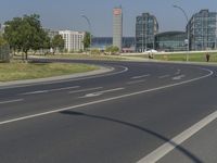 the street with two cars is empty in front of some city buildings by water in a sunny day