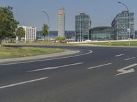 the street with two cars is empty in front of some city buildings by water in a sunny day