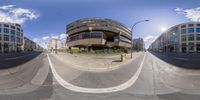 a large circular building sitting on top of a road next to tall buildings of some sort