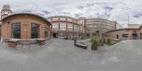 a view from the camera looking at buildings and a sky background behind it in the middle of a wide panoramic photo