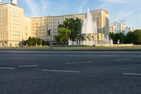 a large building with a fountain in the middle of the street in front of it