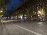 a city street at night with a light shining on the side, traffic under an overpass