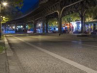 a city street at night with a light shining on the side, traffic under an overpass