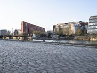 a cobblestone street in front of some high rise buildings and a television tower