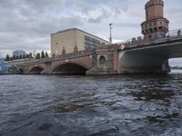 large body of water next to a building near the river with people on it and boats in the water