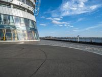 the sky is blue and clear outside of a building that has glass front windows overlooking a body of water