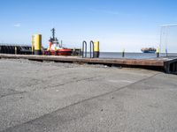 there is a ship in the water, at the dock, with yellow poles on the ground