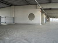 an empty parking garage with metal flooring and large circular window in center of room