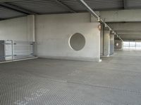 an empty parking garage with metal flooring and large circular window in center of room