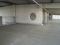 an empty parking garage with metal flooring and large circular window in center of room