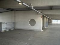 an empty parking garage with metal flooring and large circular window in center of room