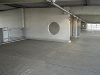 an empty parking garage with metal flooring and large circular window in center of room