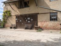 an open wooden door on an old building outside with a bench and wagon attached to it