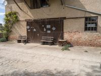 an open wooden door on an old building outside with a bench and wagon attached to it