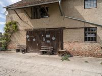 an open wooden door on an old building outside with a bench and wagon attached to it