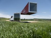 a large container house in a field with no roof and windows that are standing in the grass