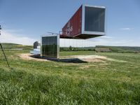 a large container house in a field with no roof and windows that are standing in the grass