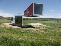 a large container house in a field with no roof and windows that are standing in the grass