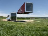 a large container house in a field with no roof and windows that are standing in the grass