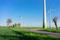 a grassy field with lots of wind turbines behind it with a bike and car in the distance