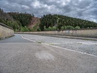 concrete walkway with trees and fenced in area on opposite sides of the road and one side of the road