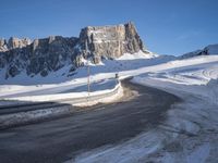 a snow covered hill sits in the distance on a road that is blocked by large snow piles