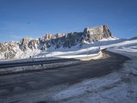 a snow covered hill sits in the distance on a road that is blocked by large snow piles