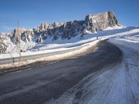 a snow covered hill sits in the distance on a road that is blocked by large snow piles