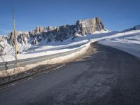 a snow covered hill sits in the distance on a road that is blocked by large snow piles