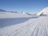 a skier goes down a snowy ski trail towards the mountains in the distance is snow covered hills