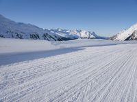 a skier goes down a snowy ski trail towards the mountains in the distance is snow covered hills