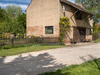 a house with a long wooden driveway in front of it and a fence around the entrance