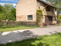 a house with a long wooden driveway in front of it and a fence around the entrance