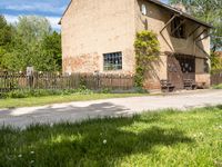 a house with a long wooden driveway in front of it and a fence around the entrance