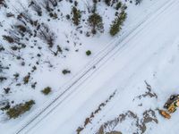 an aerial view of a truck on a snow covered road, in the middle of a forested area