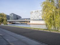 an empty street next to two large buildings and trees next to a river that passes over