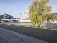 an empty street next to two large buildings and trees next to a river that passes over