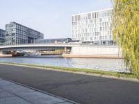 an empty street next to two large buildings and trees next to a river that passes over