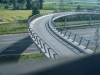 a winding curved highway passing over a bridge in rural landscape setting, viewed through car window