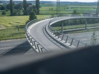 a winding curved highway passing over a bridge in rural landscape setting, viewed through car window