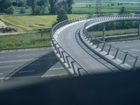 a winding curved highway passing over a bridge in rural landscape setting, viewed through car window