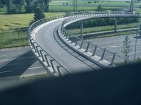 a winding curved highway passing over a bridge in rural landscape setting, viewed through car window