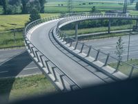 a winding curved highway passing over a bridge in rural landscape setting, viewed through car window